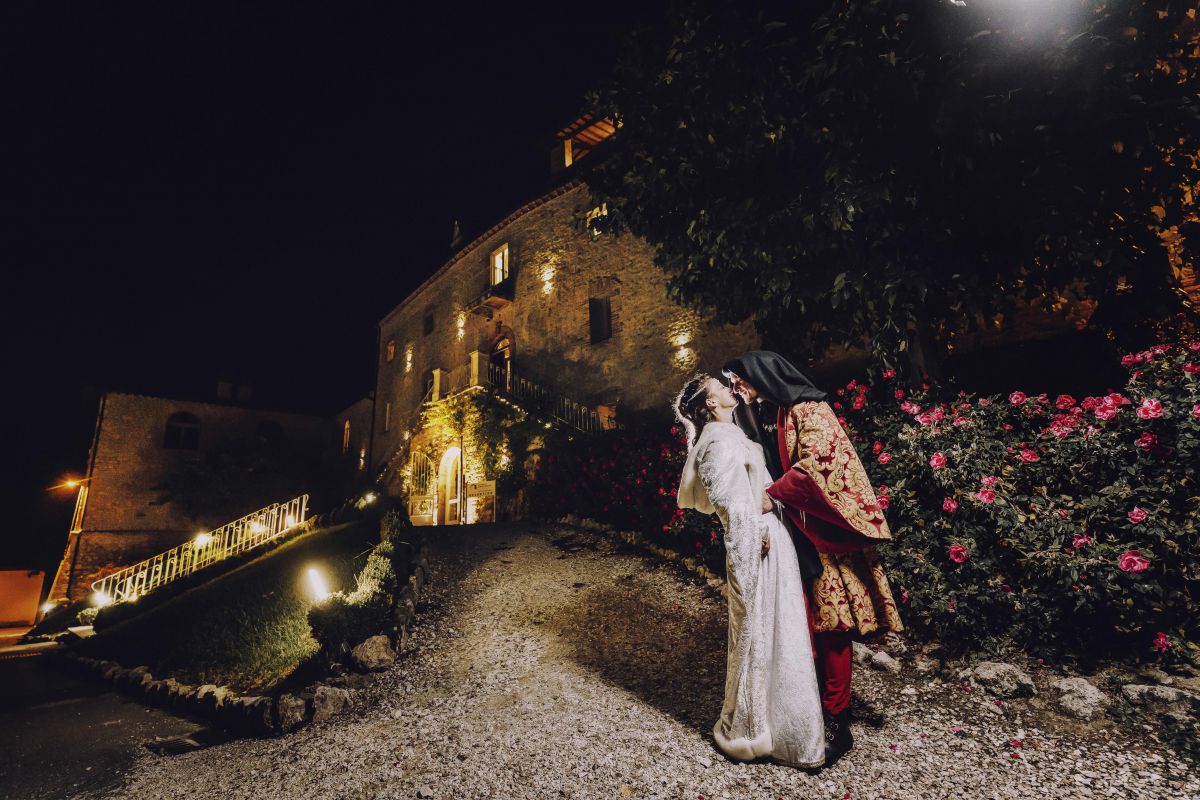 Il matrimonio medievale di Alessandro e Roberta. Alle spalle dei due sposi, la facciata principale del Castello di Montignano, la loro location wedding