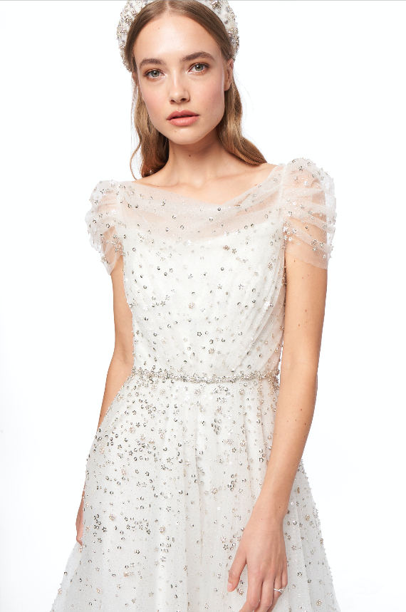 In questa foto una modella indossa un abito da sposa bianco con micro e maxi paillettes argento di Jenny Packham 2021