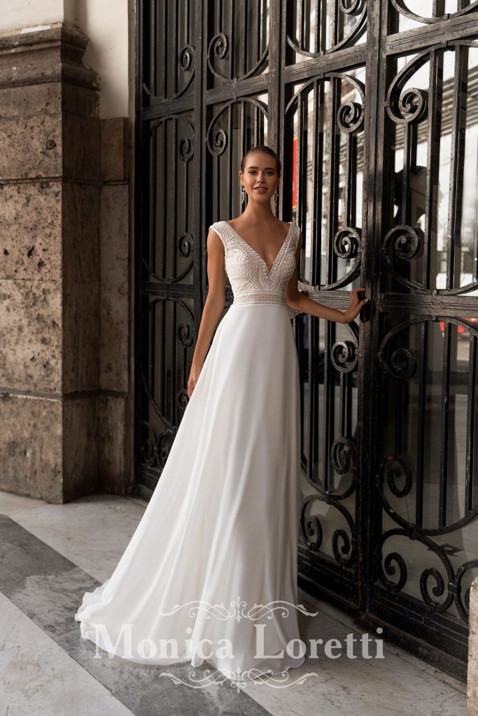 In questa foto una modella indossa un abito da sposa semplice di Monica Loretti