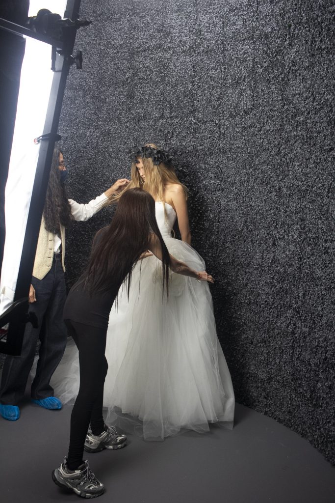 In questa foto la stilista sistema l'abito della modella che indossa uno dei suoi abiti da sposa per lo shooting fotografico della nuova collezione 