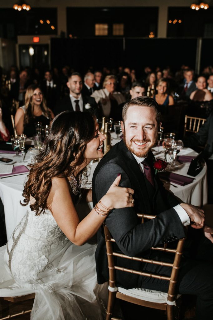 In questa foto due sposi ridono seduti al tavolo con alcuni ospiti durante il ricevimento