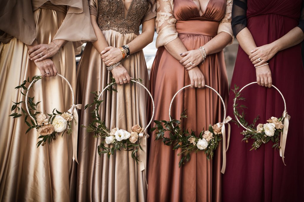 In questa foto 4 damigelle in abito lungo tengono nella mano destra un bouquet