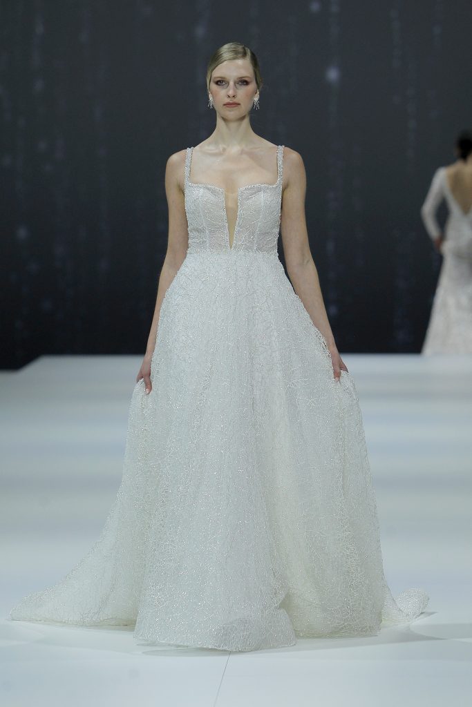 In questa foto la modella indossa un abito da sposa Nicole Milano 2023 con scollo quadrato.