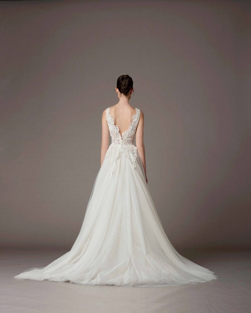 In questa foto una modella indossa un abito da sposa schiena scollata 2022 della collezione Antonio Riva con pizzo nello scollo.