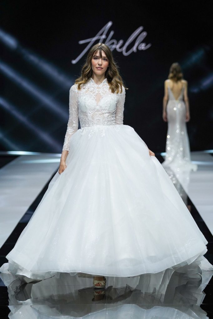 In questa foto la modella indossa un abito da sposa con maniche lunghe di pizzo e gonna di tulle.