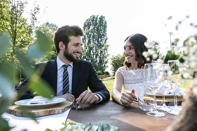 In questa foto una coppia di sposi al tavolo nuziale, in un matrimonio eco-friendly organizzato da Simona Villa