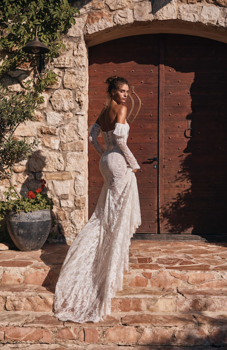 In questa foto una modella sale le scale indossando uno degli abiti da sposa 2023 di punta della collezione Gali Karten 