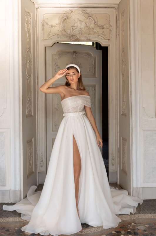 In questa foto una modella con un abito da sposa monospalla con spacco della collezione Pollardi 2023