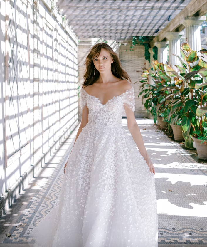 In questa foto una modella posa con un abito da sposa romantico della collezione Verdin Bridal 2023