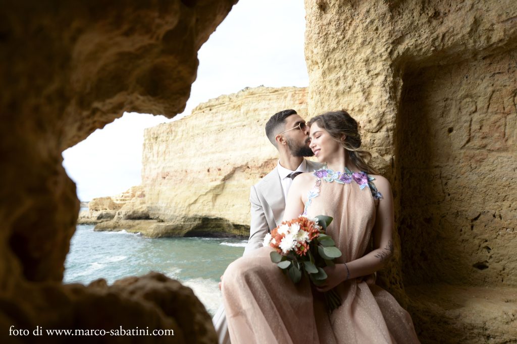 In questa foto uno shooting in spiaggia in Portogallo realizzato da Wedding by Elisa: gli sposi tra le rocce dell'Algarve