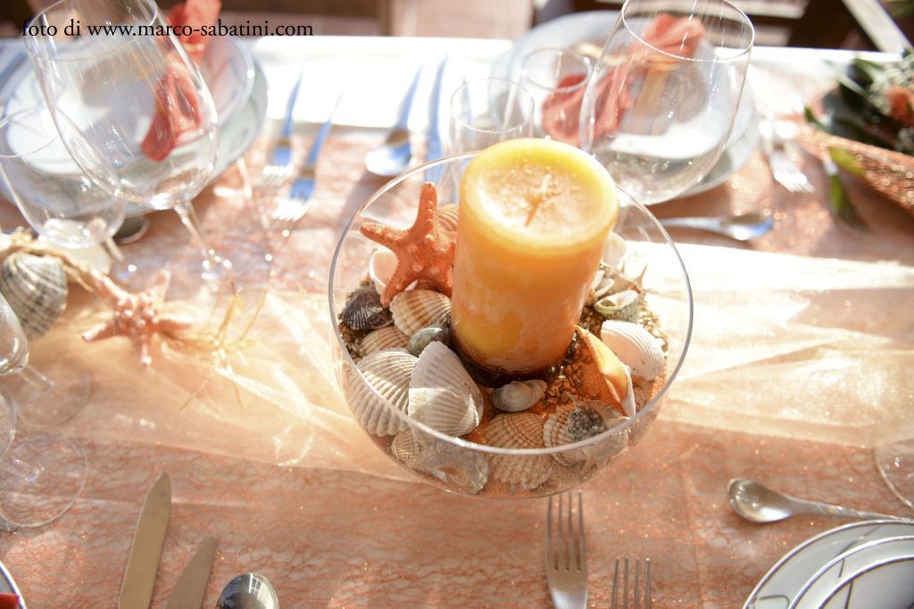 In questa foto un centrotavola con candele e conchiglie allestito da Wedding by Elisa per un matrimonio al mare in Portogallo