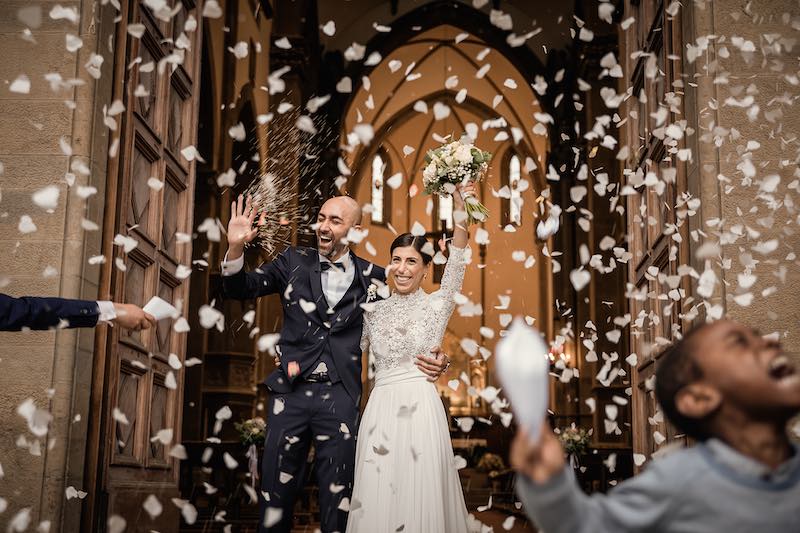 In questa foto di Nicola Tanzella due sposi escono dalla chiesa durante il lancio di riso e petali