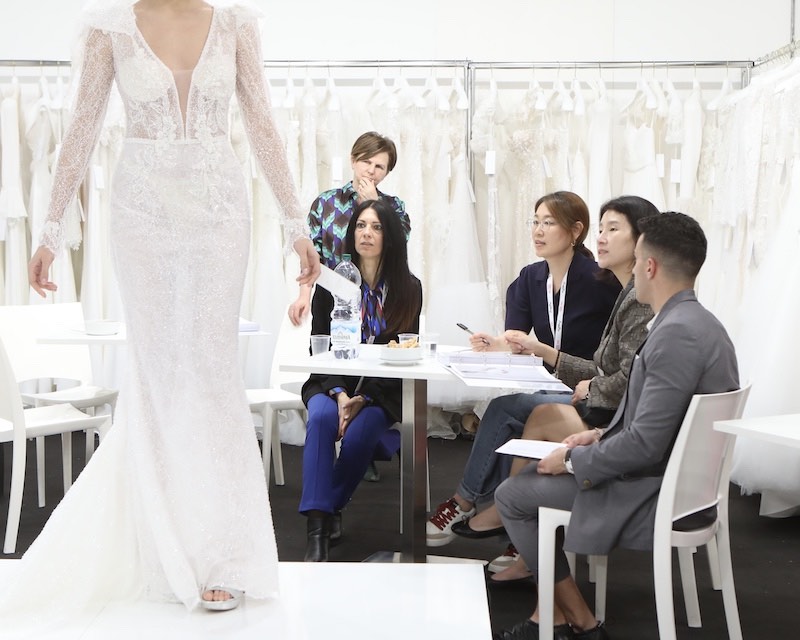 In questa foto buyer a bordo passerella osservano una modella che sfila alla Rome Bridal Week 2023