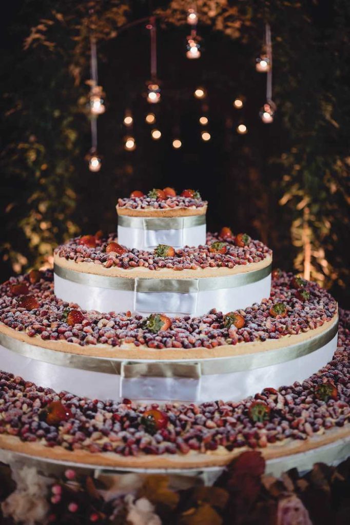 In questa foto una torta a piani separati decorati con frutti di bosco e nastri di nastri di colore argento
