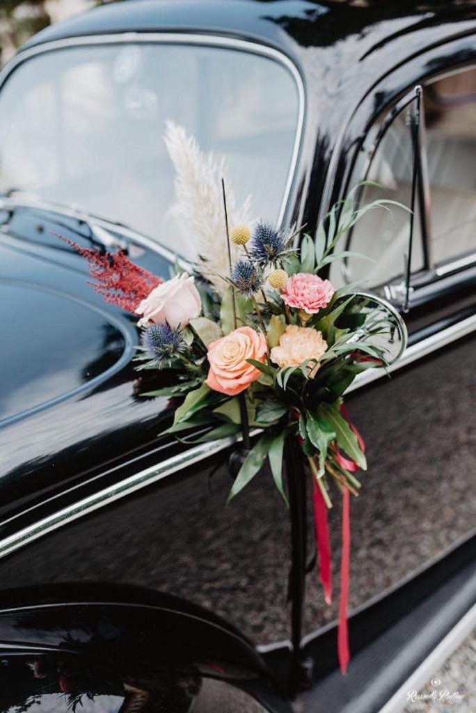 In questa foto il dettaglio della decorazione dell'auto degli sposi realizzata da Idee da Sogno con palme e rose di colore bianco e rosa