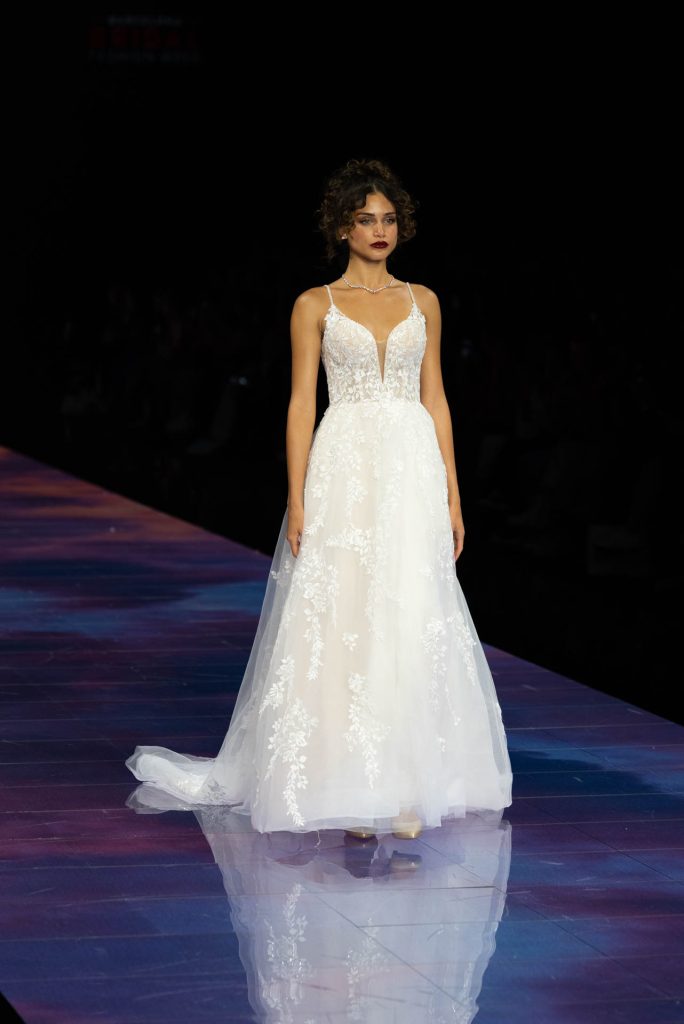 In questa immagine una modella indossa un abito da sposa Demetrios 2024 con ricami floreali in pizzo 