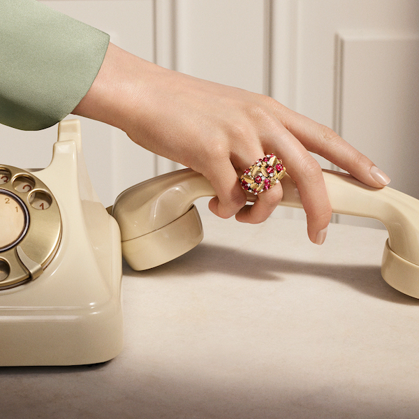 In questa foto la mano di una modella mentre poggia la cornetta di un vecchio telefono: sull'anulare sfoggia un maxi anello Cartier, della linea di gioielli femminili 2023