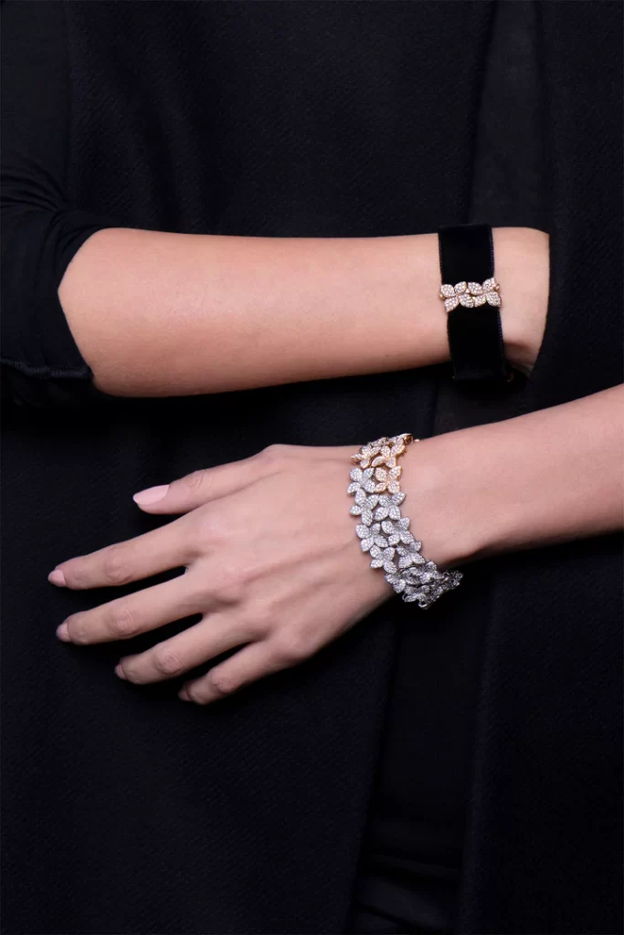 In questa foto una modella mostra due bracciali in oro e diamanti, con forme floreali, della collezione Pasquale Bruni 