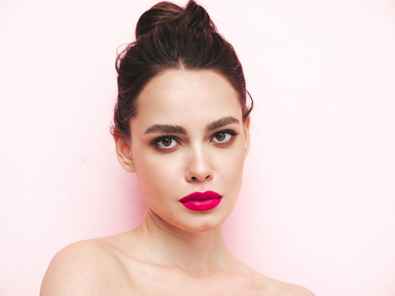 In questa foto una modella con un make up Barbiecore con rossetto di colore fucsia