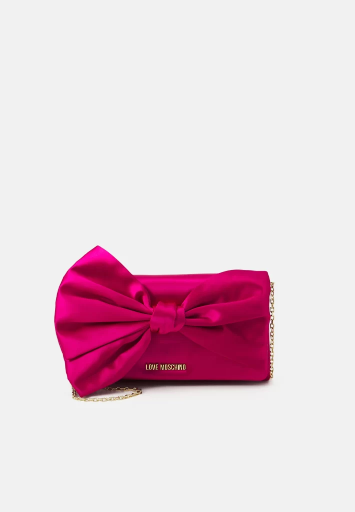 In questa foto una clutch Moschino di colore fucsia con fiocco frontale