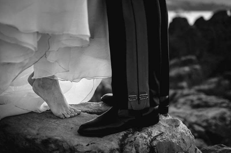 In questa foto in bianco e nero di Alberto Cosenza i piedi di due sposi su uno scoglio. La sposa è in punta di piedi mentre lo sposo indossa la divisa d'ordinanza da carabiniere 