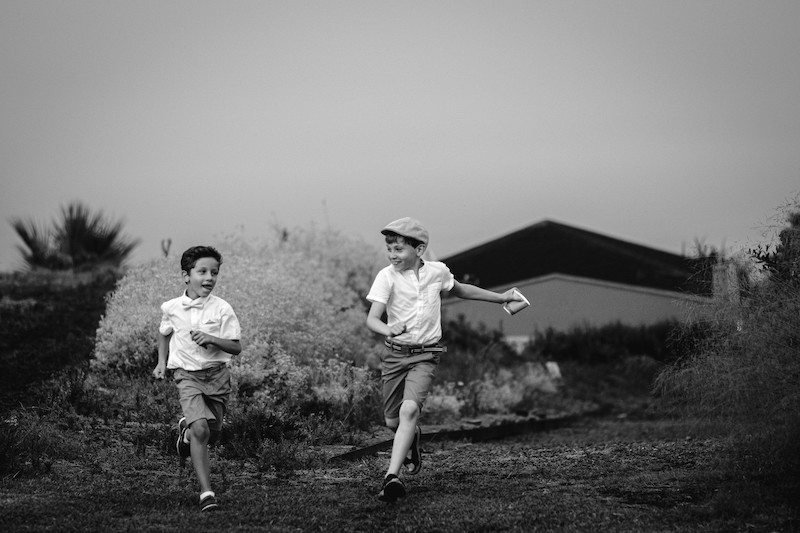 In questa foto in bianco e nero due bambini con pantaloncini e coppola che corrono su un prato