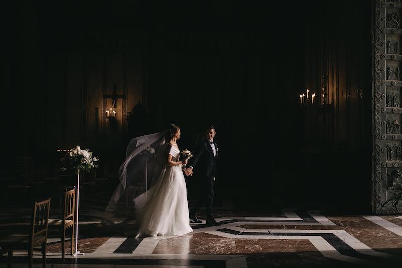 In questa foto di Alberto Cosenza due sposi che si guardano sorridendo mentre escono dalla chiesa dove è stato celebrato il loro matrimonio