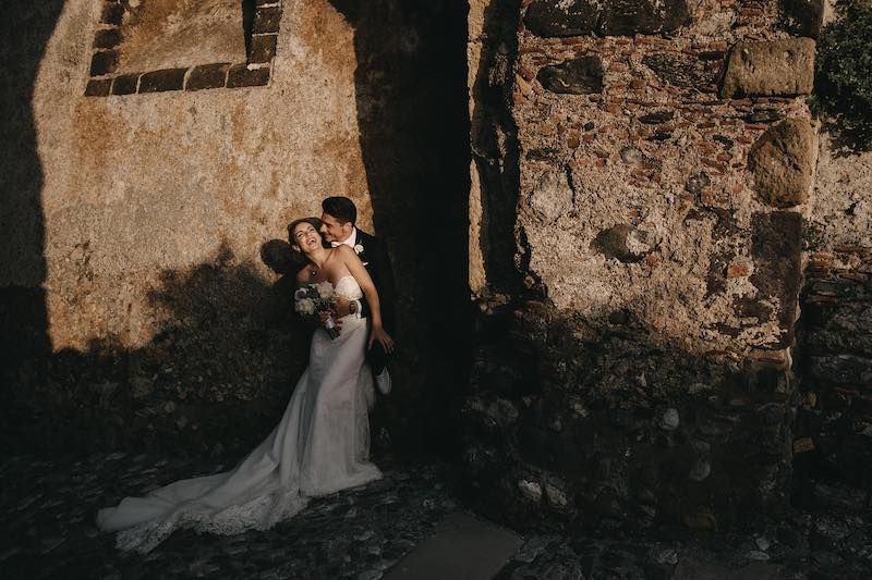 In questa foto di Alberto Cosenza due sposi ridono mentre si abbracciano tra le vie di un paese