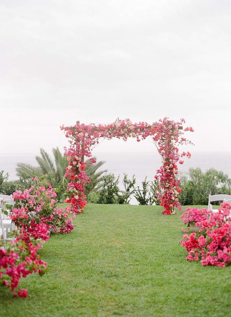 In questa foto l'allestimento di un matrimonio civile su un prato con decorazioni floreali di colore rosa e fucsia lungo il corridoio centrale e sulla struttura dell'altare 