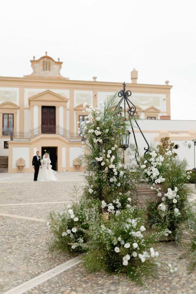 In questa foto l'atrio di Villa del Gattopardo decorato con fiori bianchi e gypsophila. Sullo sfondo si intravedono due sposi