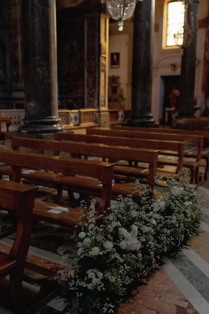 In questa foto il dettaglio delle decorazioni di fiori bianchi del matrimonio di Elena e Nicola, disposte lungo la navata della chiesa di Sant'Ignazio all'Olivella a Palermo