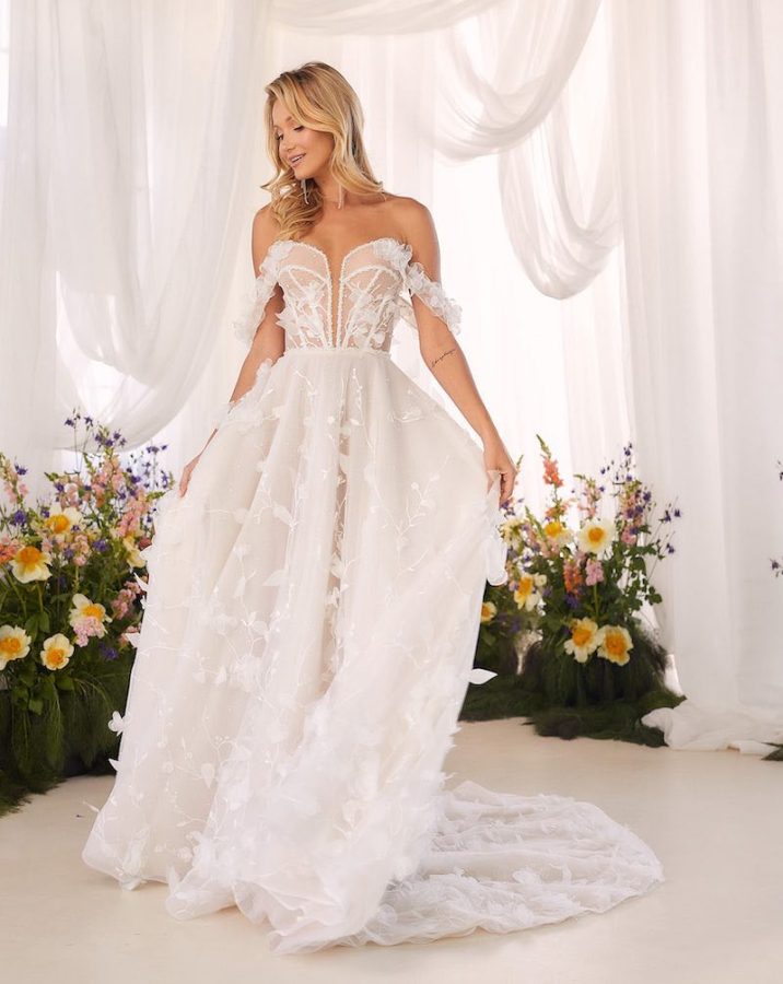 In questa foto una modella indossa un abito da sposa scivolato con fiori 3D e scollo a cuore off shoulder di Agnieszka Swiatly 