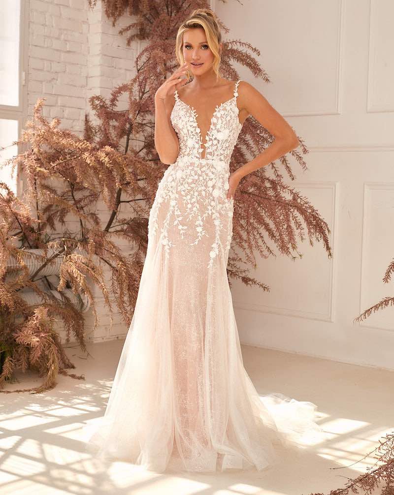 In questa foto una modella indossa un abito da sposa a sirena Agnieszka Swiatly in tulle glitter di colore rosa tenue con scollo a cuore e piccoli fiori 3D che scendono dal corpetto fino a metà gonna