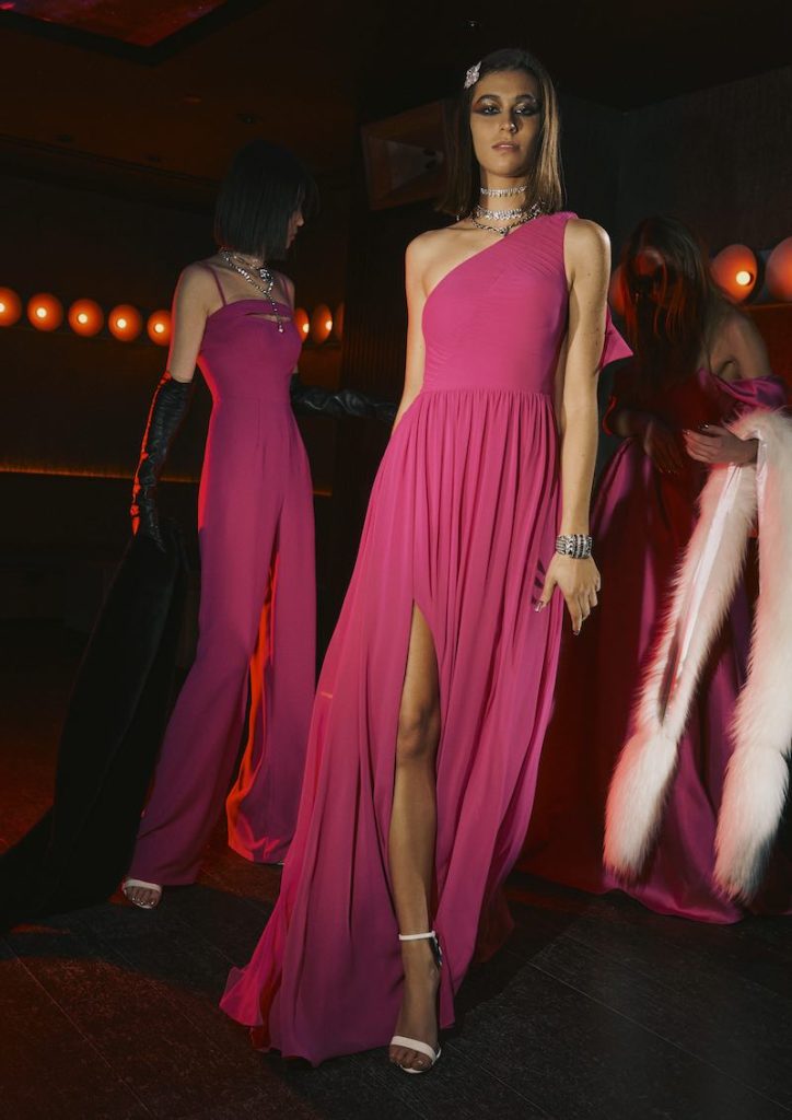 In questa foto una modella indossa un abito da damigella Vera Wang 2024 con scollatura monospalla di colore fucsia