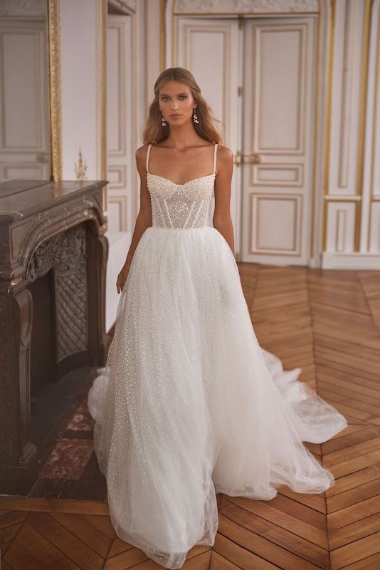 In questa foto una modella indossa un abito da sposa Milla Nova 2024: la gonna è scivolata e vaporosa, in tulle; il bustier, con micro perle applicate all over, ha una scollatura quadrata e bretelle super sottoli