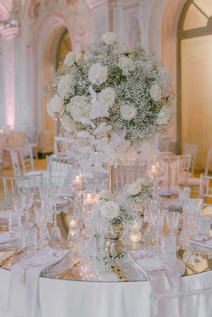 In questa foto la mise en place total white con dettagli di colore oro ed elementi riflettenti del ricevimento del matrimonio di Carlotta e Federico realizzato da Giovanna Damonte nella Galleria delle Stagioni a Villa Faraggiana 