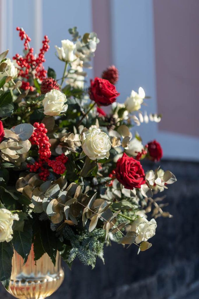 In questa foto una composizione di rose di colore bianco e rosso, bacche,  eucalipto e pungitopo posto davanti alla chiesa del matrimonio di Matteo e Pina allestito dal Wedding Planner Stefano Miranda