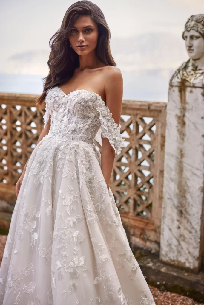 In questa foto la modella indossa un abito da sposa con decori floreali Pollardi 2024.