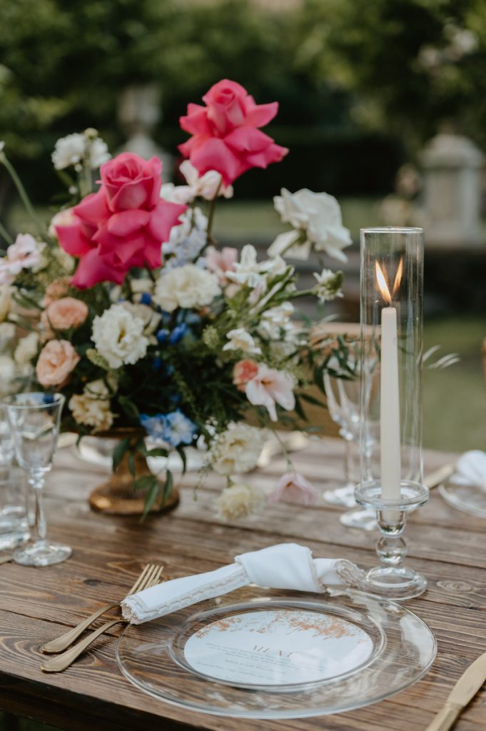 In questa foto una mise en place con piatto trasparente e coppe di fiori colorati come centrotavola, firmata da Tania Costantino Wedding Planner