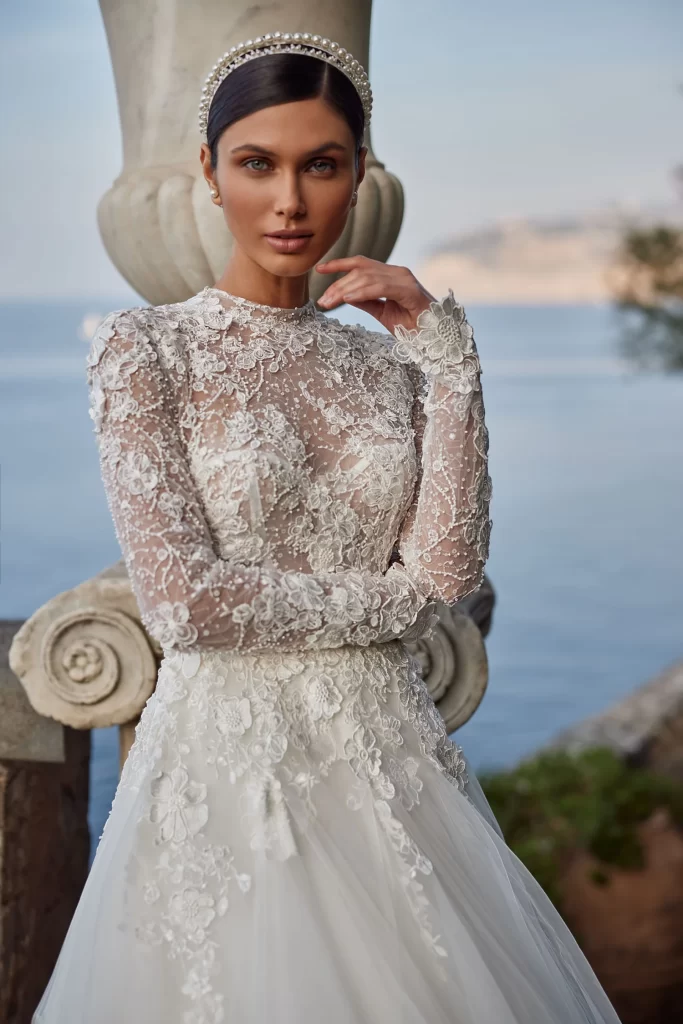 In questa foto la modella indossa un abito da sposa Pollardi 2024 di pizzo a maniche lunghe.