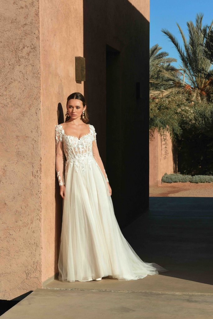 In questa immagine un abito da sposa con corpetto in pizzo e maniche floreali. 