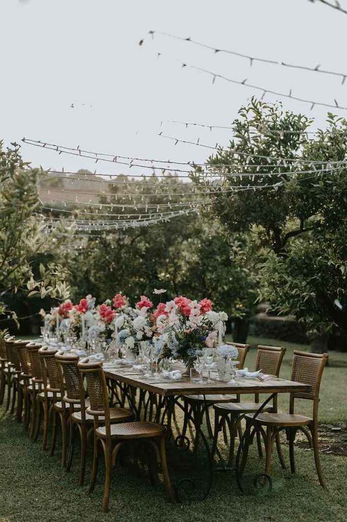 In questa foto la mise en place di un Elopement Wedding in Sicilia progettato da Tania Costantino con fiori di colore rosso, celeste e bianchi 