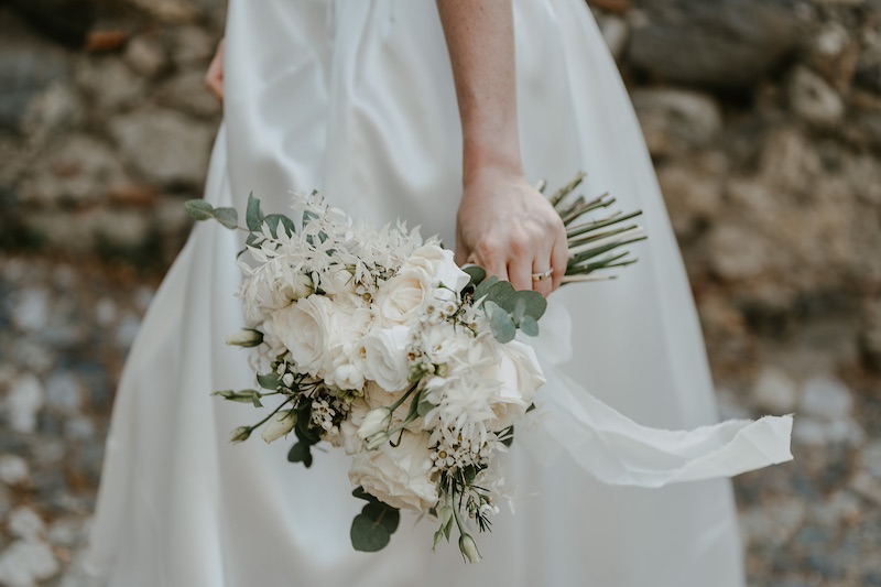 In questa foto un bouquet da sposa con fiori di colore bianco e foglie di eucalipto