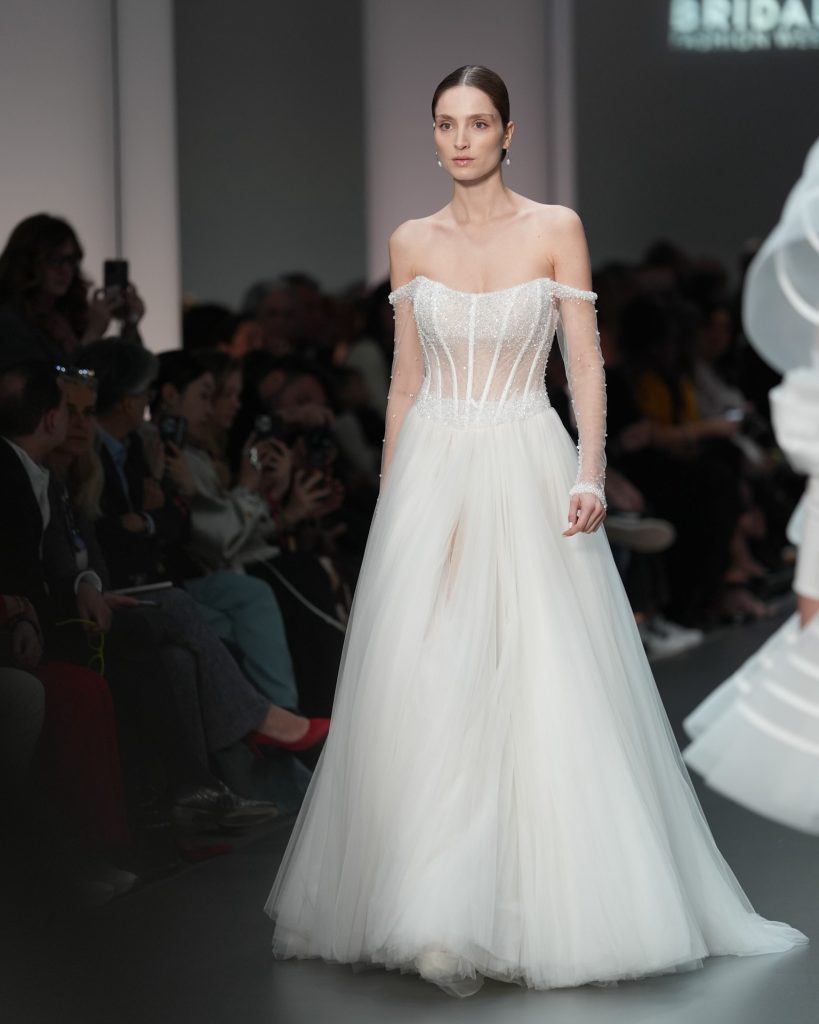 In questa immagine un abito da sposa Helena 2025 con bustier e maniche preziose. 