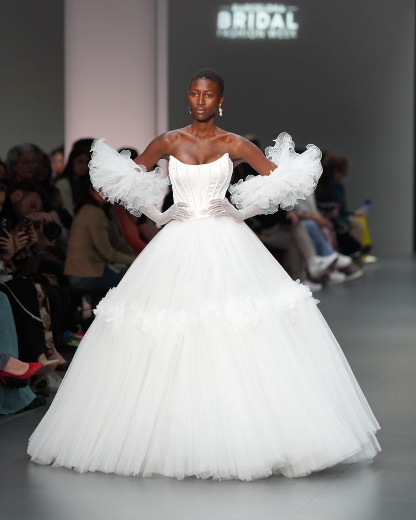 In questa immagine un abito da sposa Helena 2025 ampio, con maniche in tulle. 