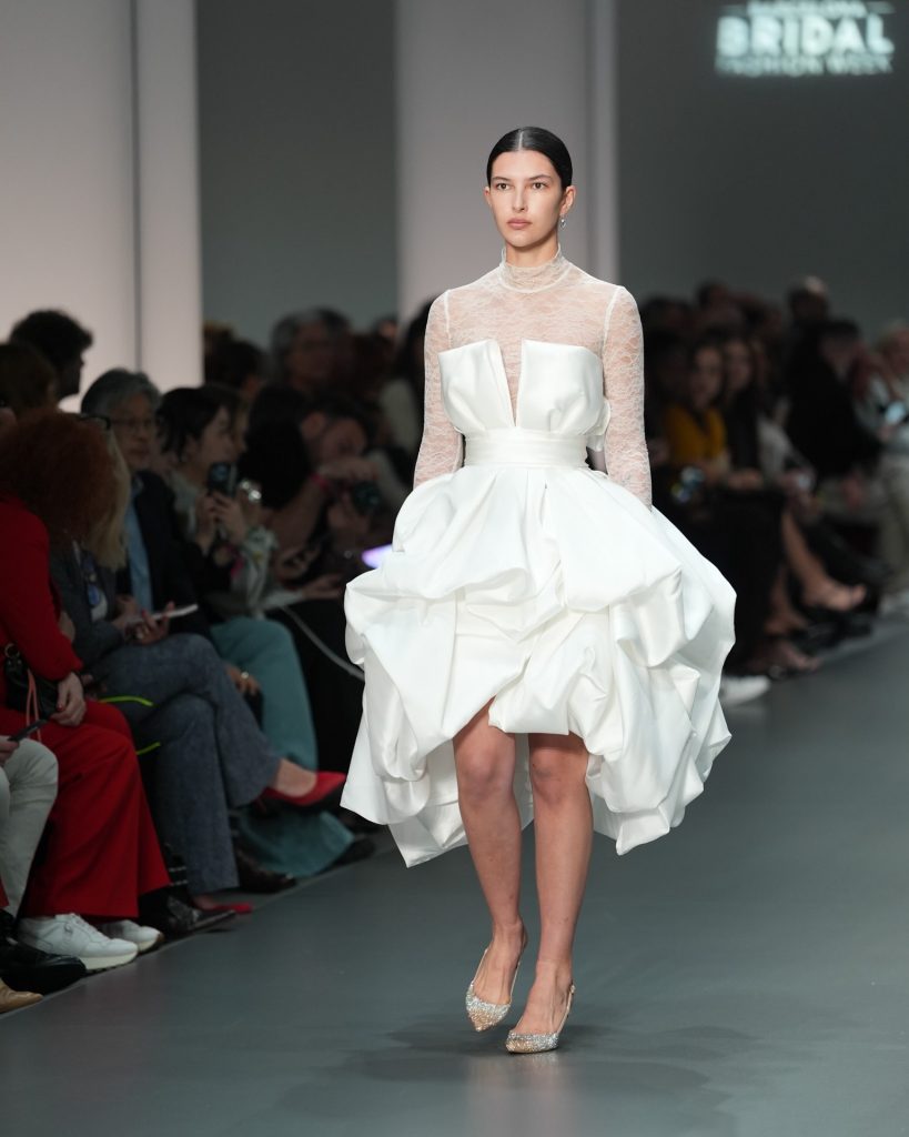 In questa immagine un vestito da sposa corto con maniche in pizzo. 