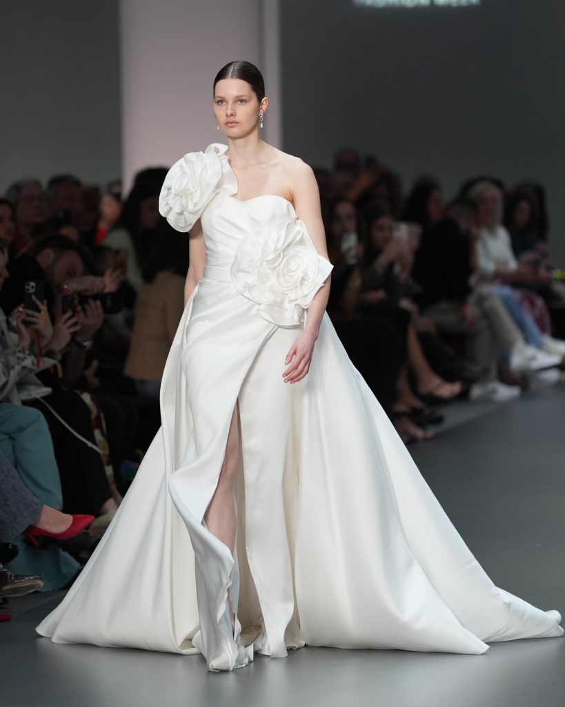 In questa immagine un abito da sposa Helena 2025 con spacco e maxi fiori in tessuto. 