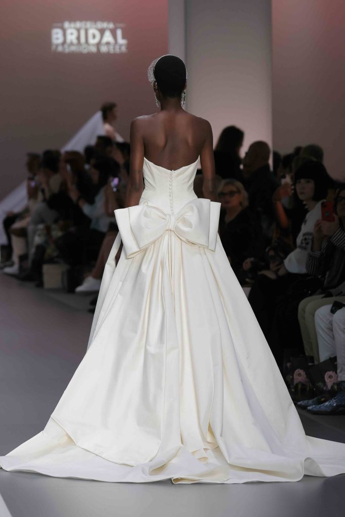 In questa immagine un abito da sposa Morilee 2025 con maxi fiocco sul retro. 