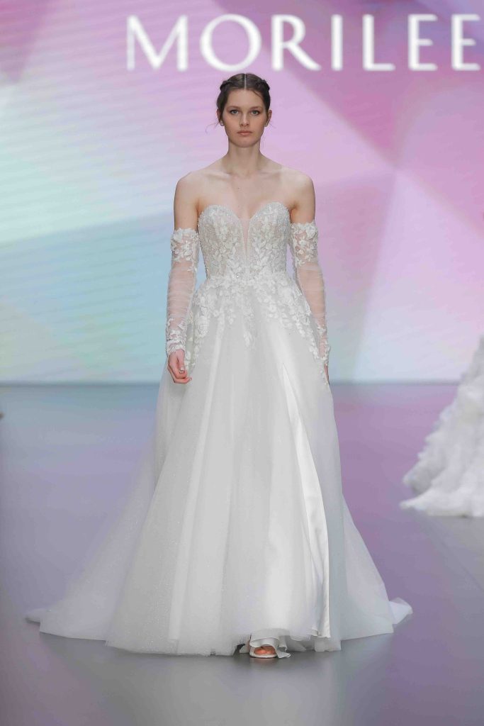 In questa immagine un abito da sposa Morilee 2025 con maniche staccabili e dettagli floreali. 