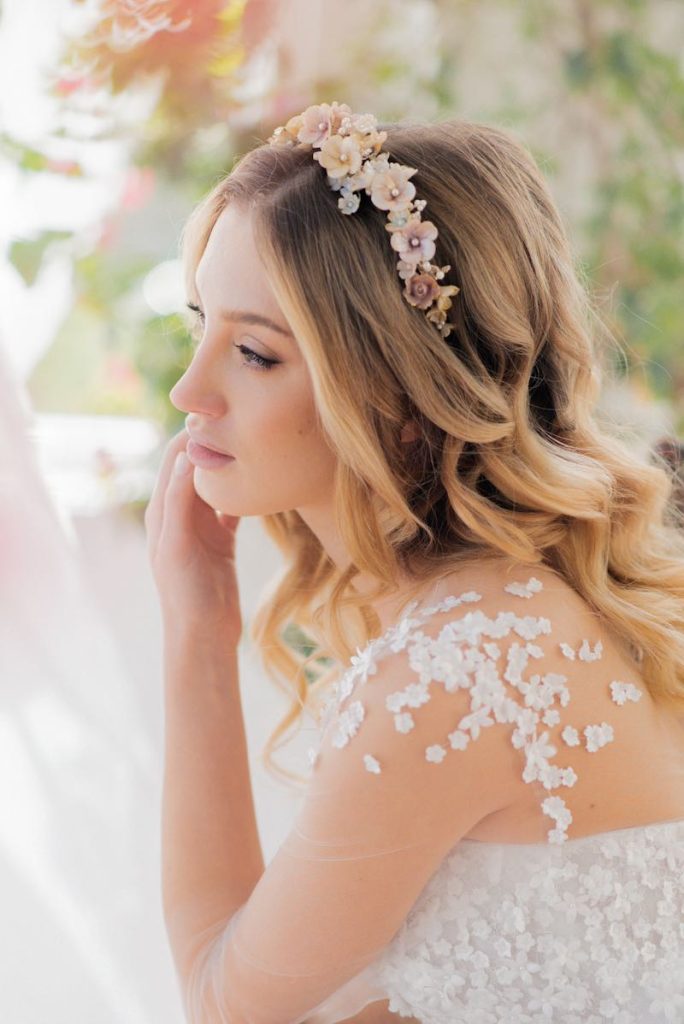 In questa foto un'acconciatura da sposa 2024 con onde e un cerchietto di fiori di colori pastello